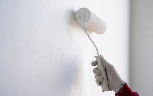 painter roller by construction worker in new cement wall