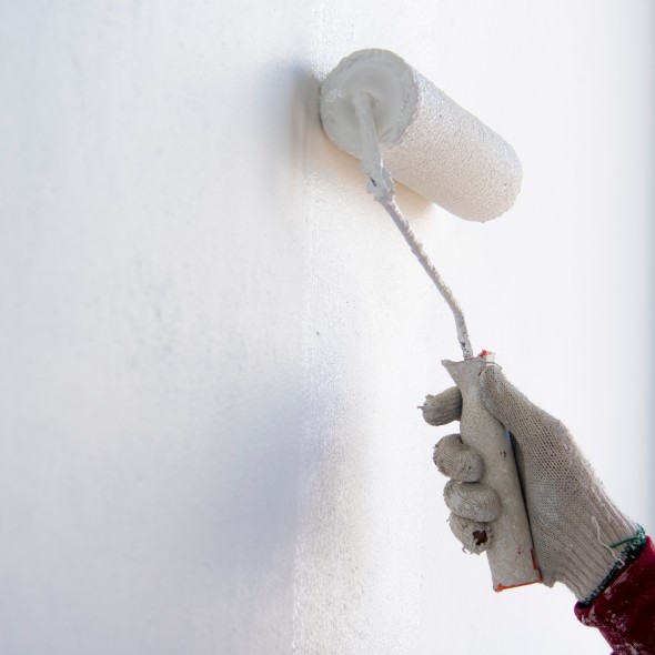 painter roller by construction worker in new cement wall