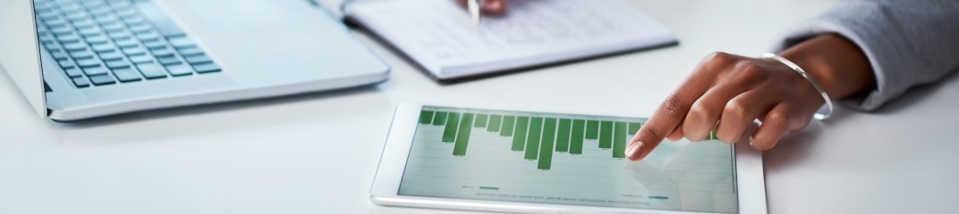 Shot of an unrecognizable businesswoman using a digital tablet with graphs on it in a modern office