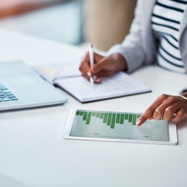 Shot of an unrecognizable businesswoman using a digital tablet with graphs on it in a modern office