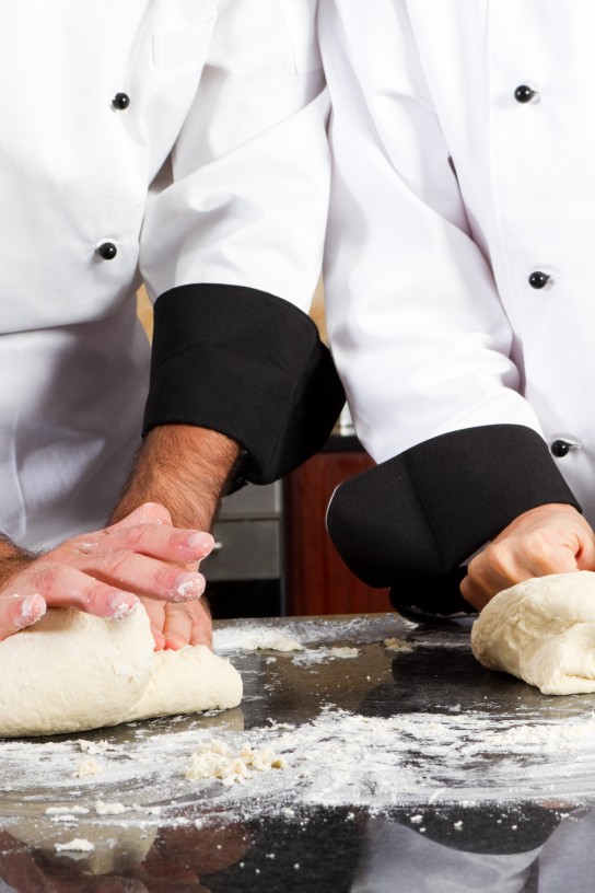 professional chef hands kneading bread dough on kitchen counter