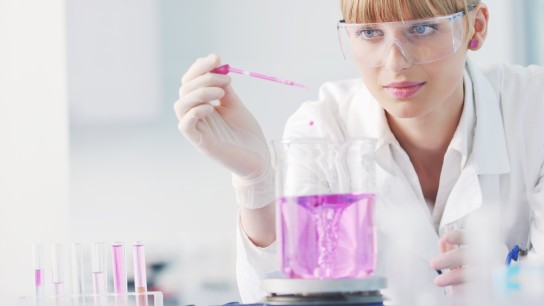 doctor student female researcher holding up a test tube in chemistry bright labaratory