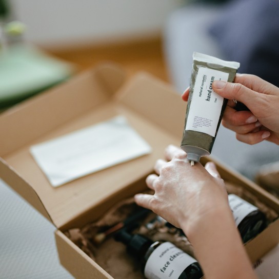 Anonymous woman holding a carton gift box on her knees. There are various natural beauty cosmetics products inside and a personal paper note.
GettyImages-1419645731.jpg