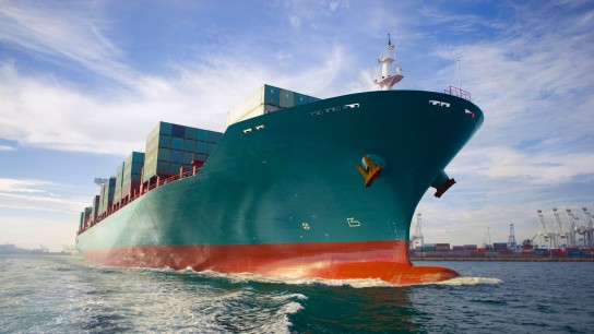 Bow-view-of-loaded-cargo-ship-sailing-out-of-port