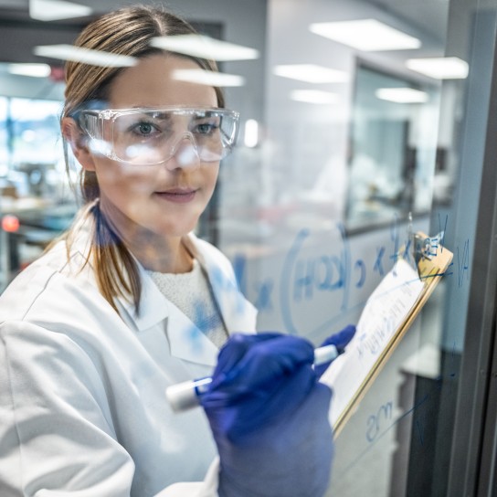 Female chemist writing formula on a glass wall, Allentown, USA