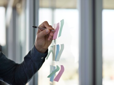 Businessman writing on paper note on glass wall