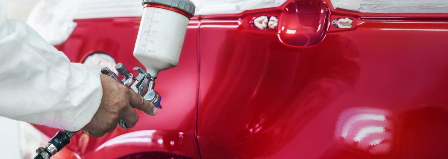 Man spraying red paint on a car