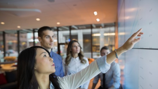 Business people pointing at projection screen