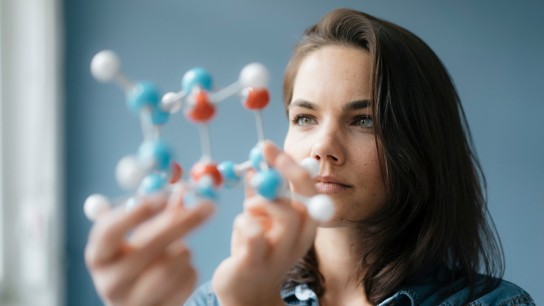Female scientist thinks about an issue with a molecule model in her hand