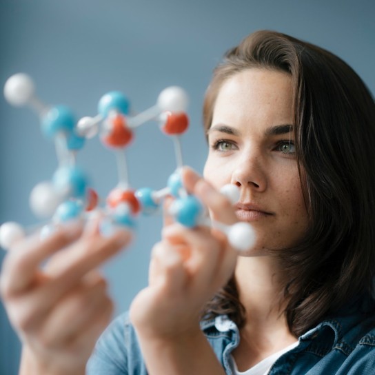 Female scientist thinks about an issue with a molecule model in her hand