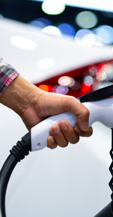 Man holding charger plug of an electric car