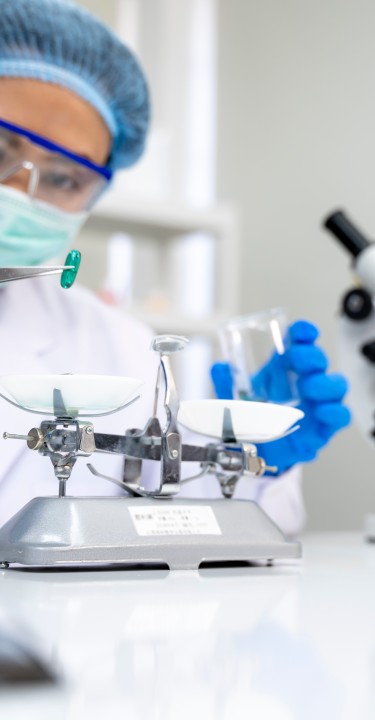 Lab technician taking pill from petri dish with lancet, pharmaceutical industry