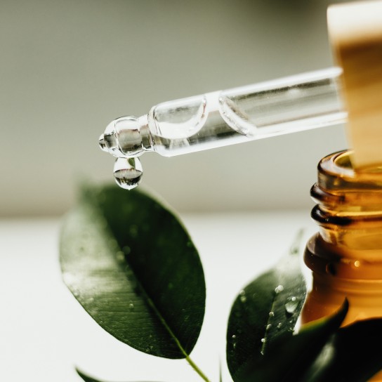 Amber bottle with serum or essential oil. Natural organic cosmetic, aromatherapy message oil. A drop of oil at the end of a pipette