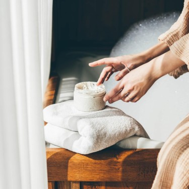 Woman taking care of her skin. Young woman in bathroom applying cream.