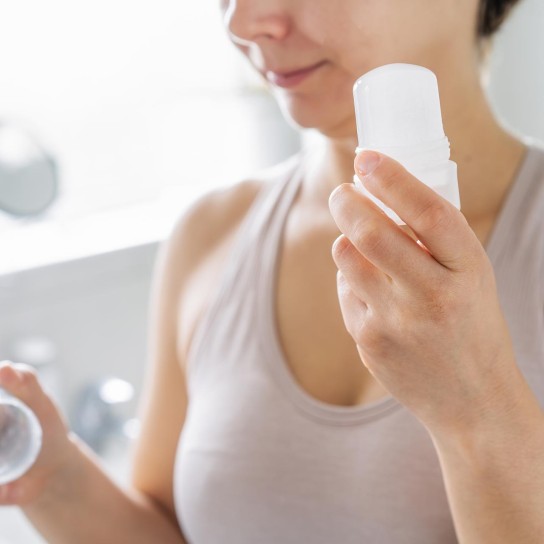 Close up woman holding natural crystal alum deodorant in modern bathroom. Eco friendly natural beauty and hygiene cosmetics. Zero waste, sustainable, alternative body care concept. Selective focus.