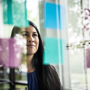 Businesswoman looking at idea notes on glass wall