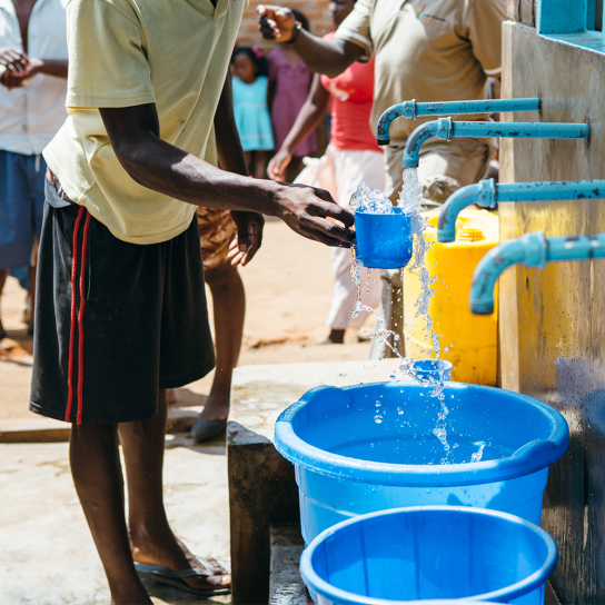 Water flowing from a tap that is being collected in blue buckets