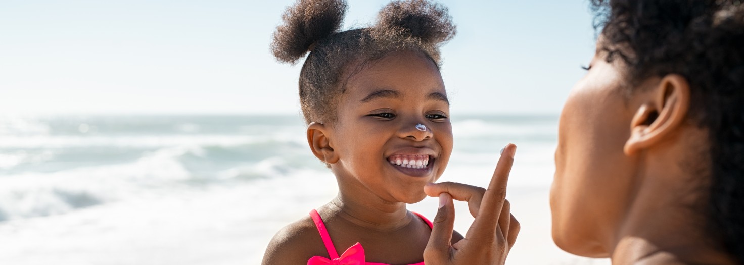 Young mother applying protective sunscreen on daughter nose at beach with copy space. Black woman hand putting sun lotion on female child face. African american cute little girl with sunblock cream at seaside.
GettyImages-1369509501.jpg