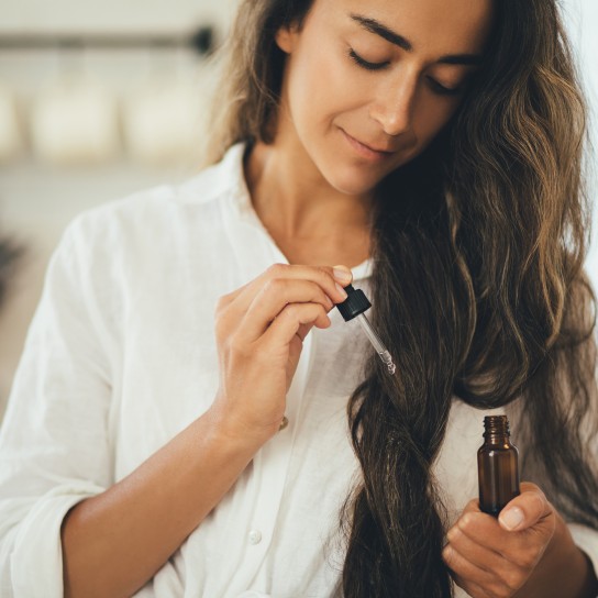 Young woman applying natural organic essential oil on hair and skin. Home spa and beauty rituals. Skin care.
GettyImages-1468539159.jpg