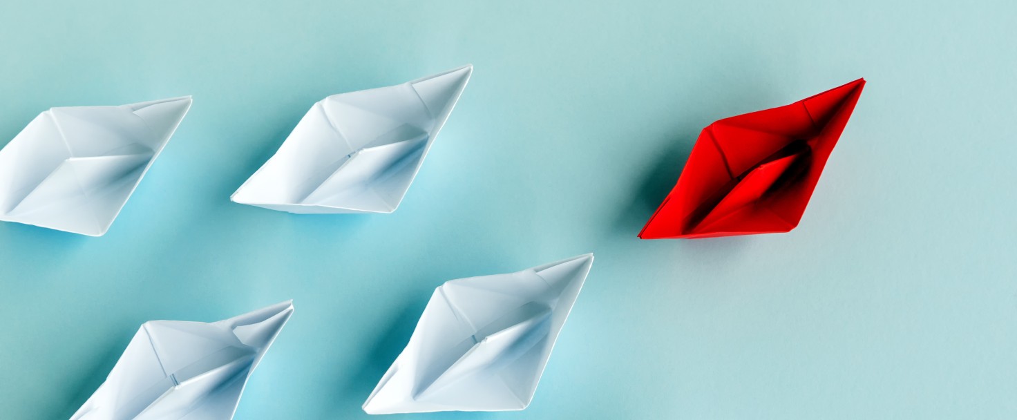 Leadership Concept - Red Paper Boat Followed by White Paper Boat on Blue Background