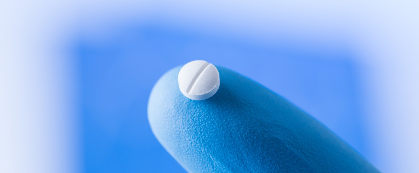 Small pill at the tip of a scientist finger in gloves, medical research concept
GettyImages-1020067918.jpg